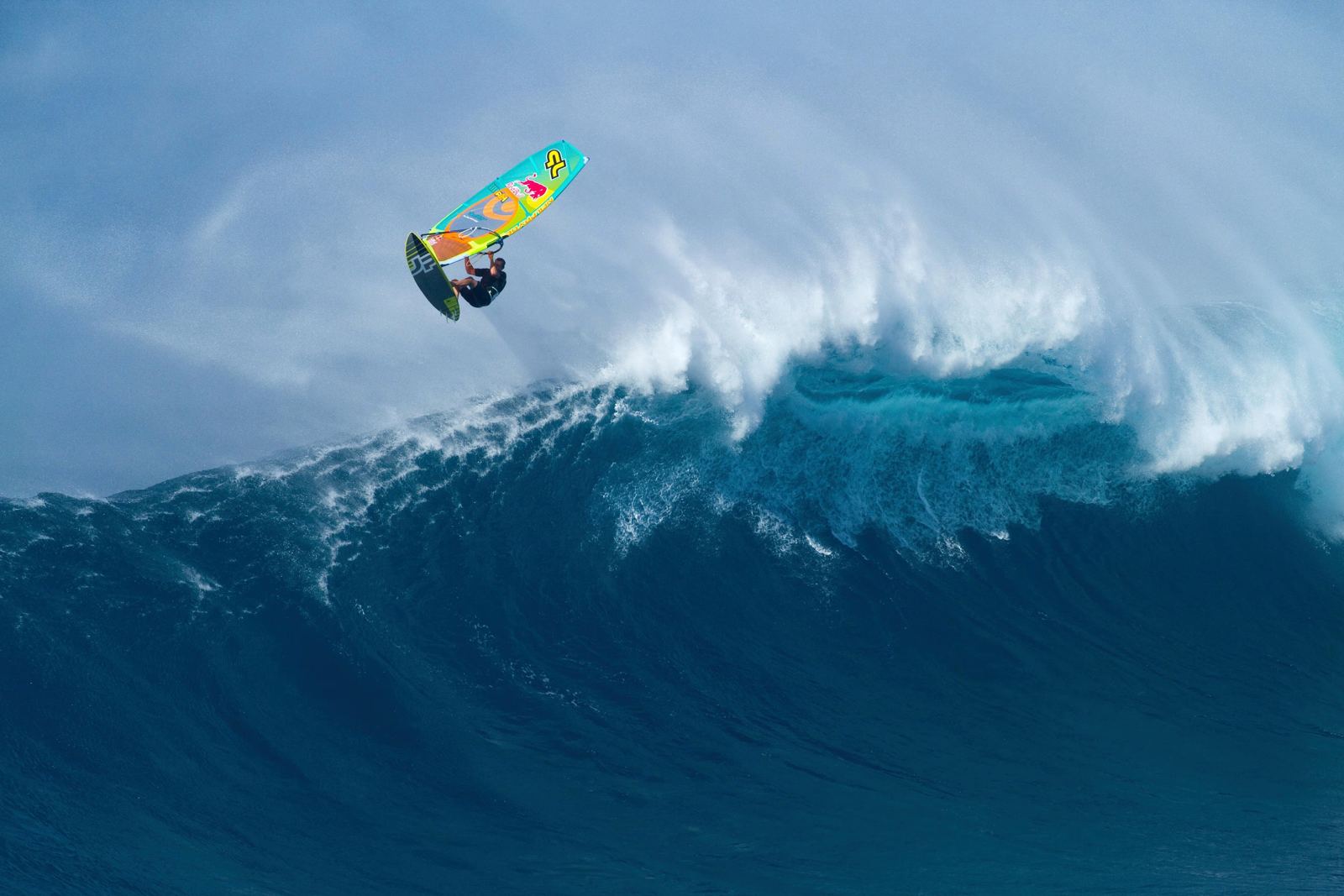 Windsurfer jumping in front of a breaking giant wave